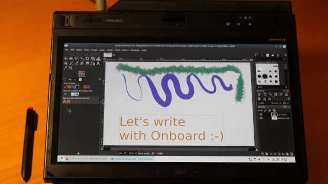 The X220 laptop in tablet mode next to the stylus, running GIMP